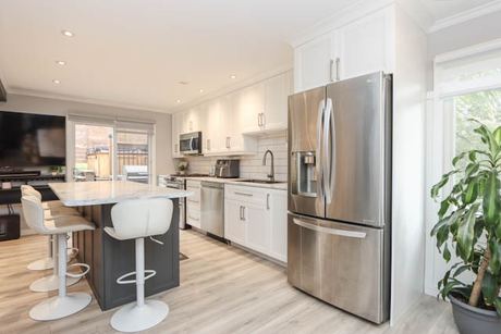 Kitchen with white cabinetry, stainless appliances and an island with bar seating