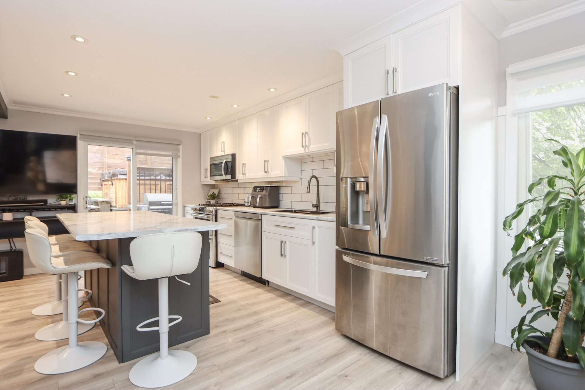 Kitchen with white cabinetry, stainless appliances and an island with bar seating
