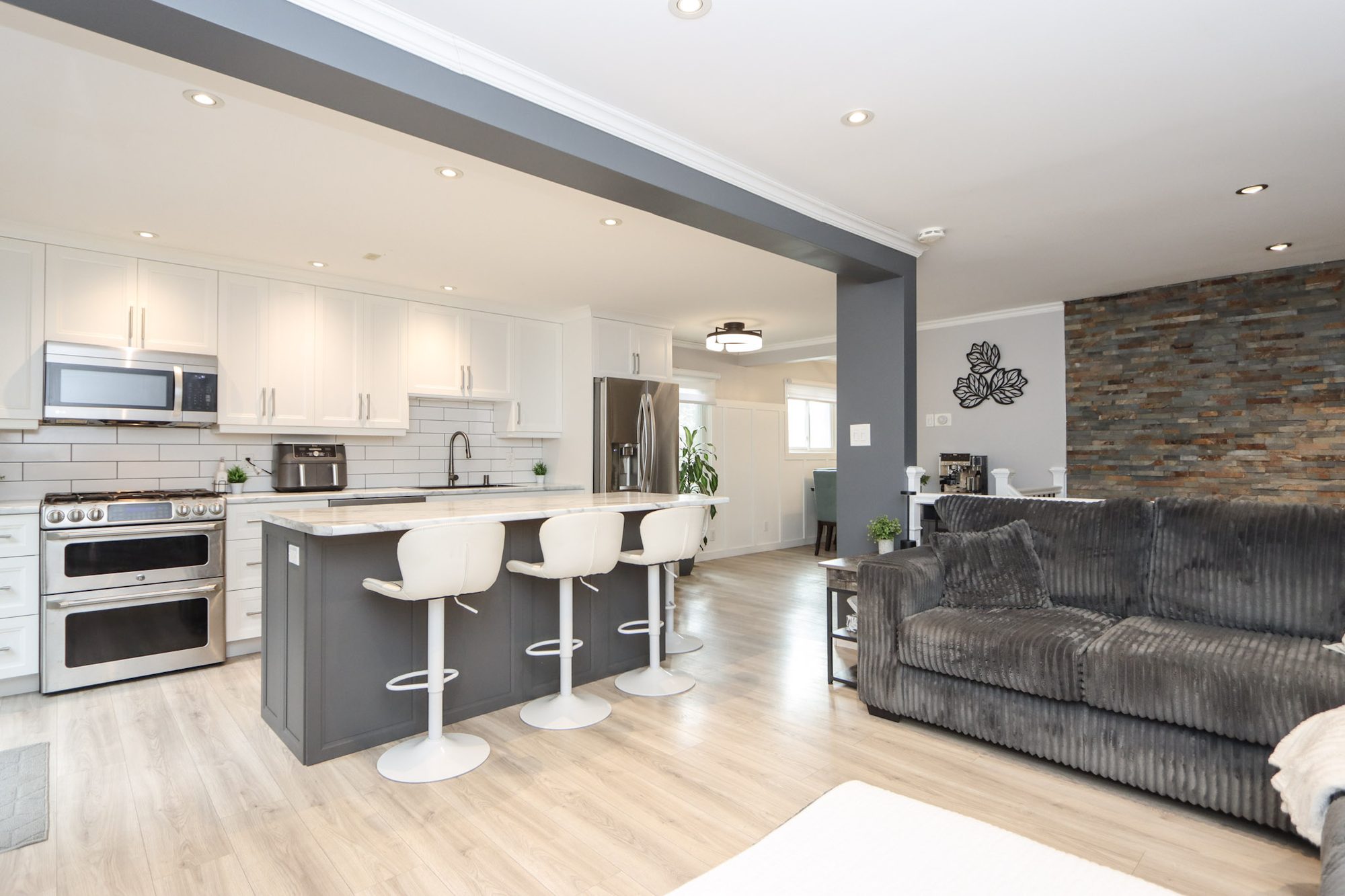 Open kitchen and living room with island seating and a stone accent wall