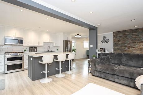Open kitchen and living room with island seating and a stone accent wall