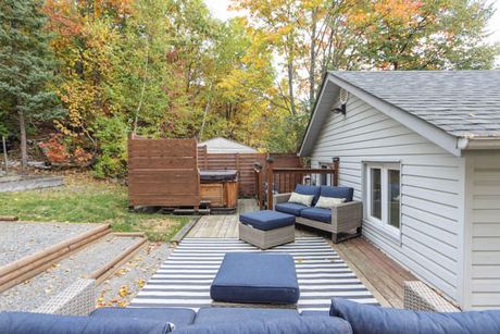 Back deck with blue seating, a hot tub and wooden privacy fencing