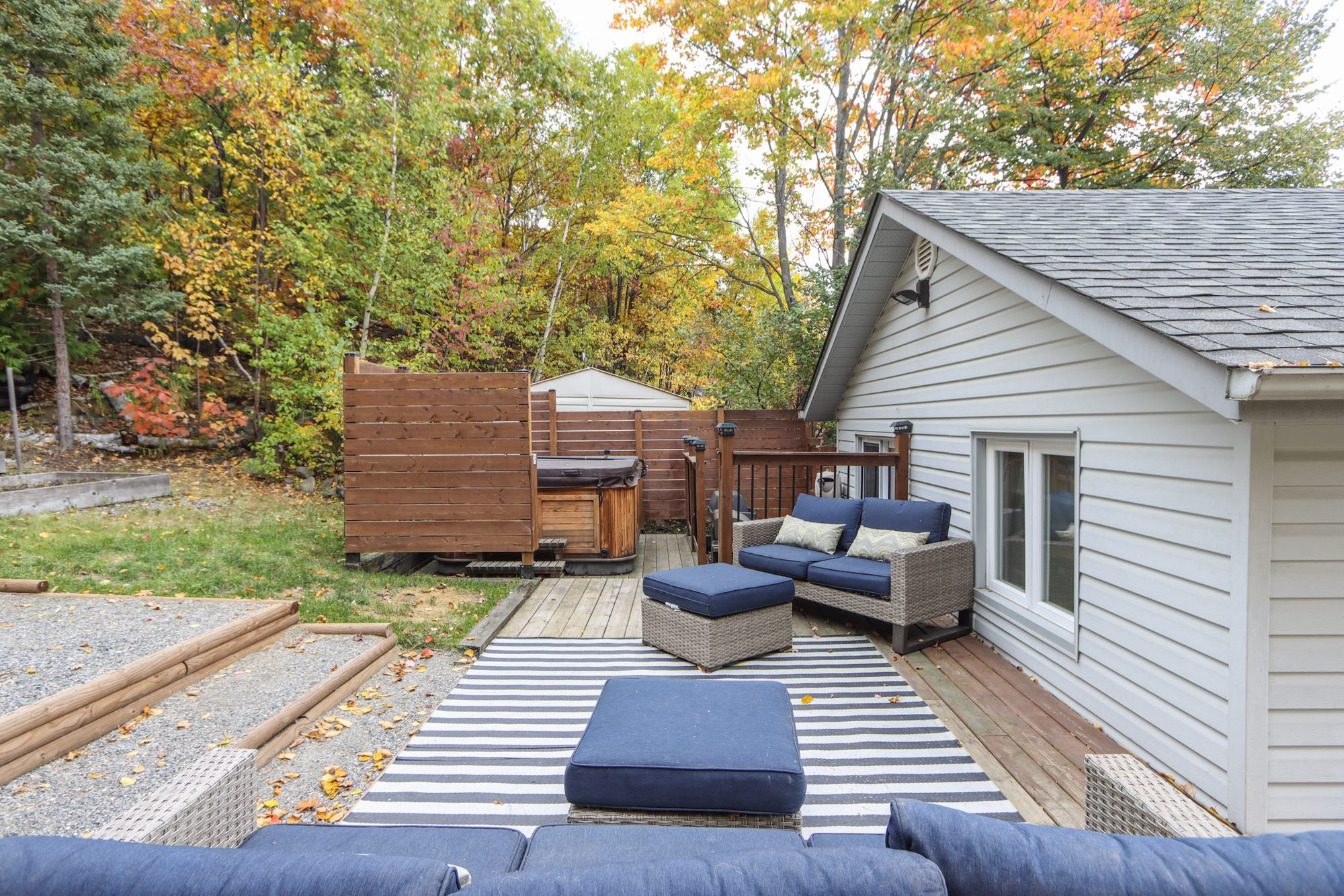 Back deck with blue seating, a hot tub and wooden privacy fencing